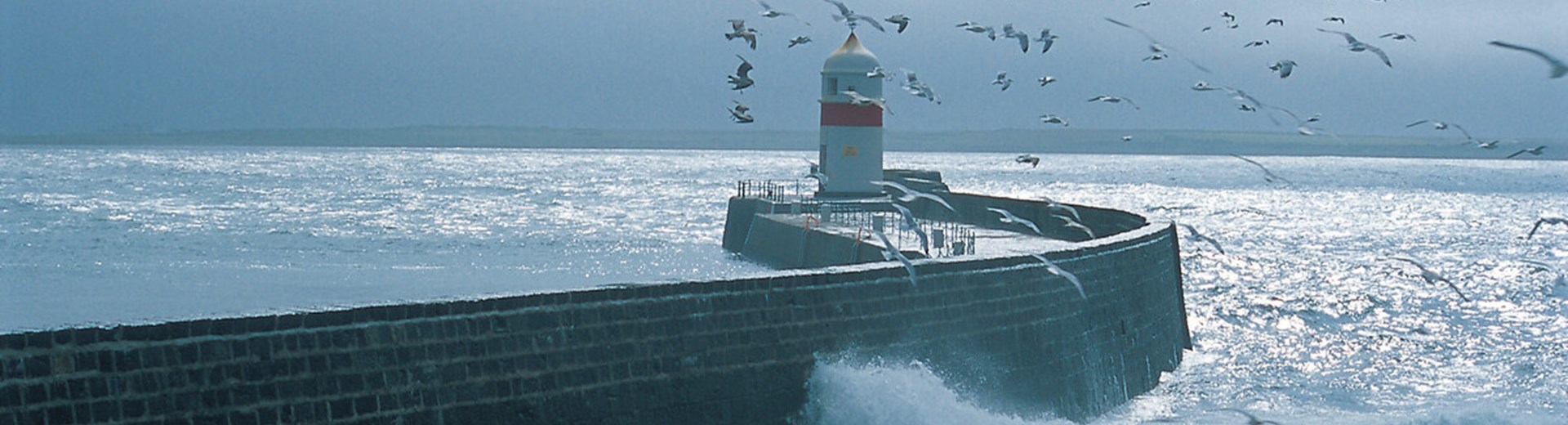 View of a white lighthouse in stormy seas on the Isle Of Man