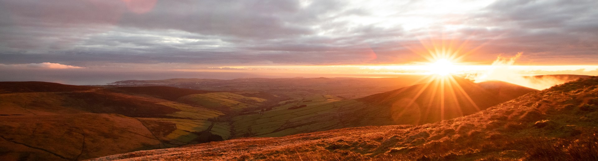 An autumnal landscape setting showing trees and a sunset over the Sloc