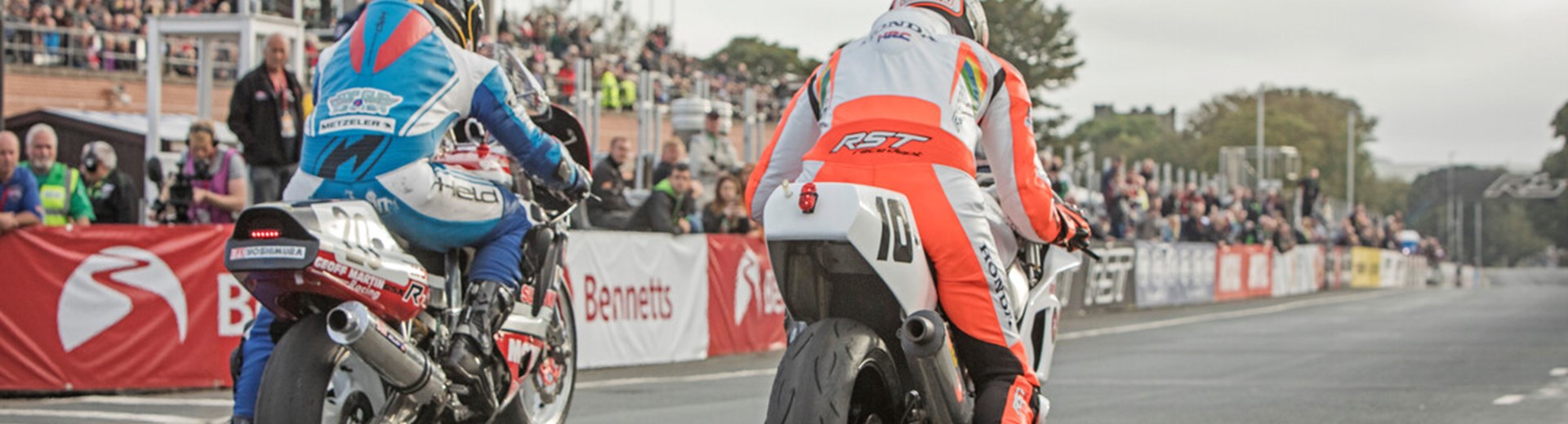 Two motorsport competitors on their motorbikes at the Isle Of Man TT Start Line. 