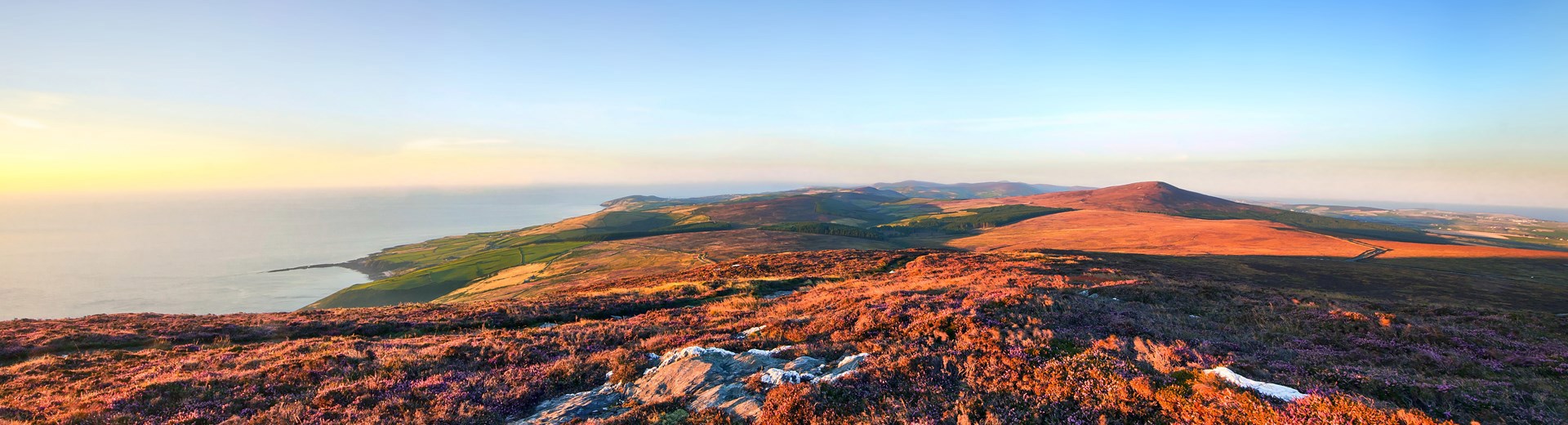 Vast body of water capturing the glow of the setting sun with mountain ridges in the distance under a vibrant coloured sky